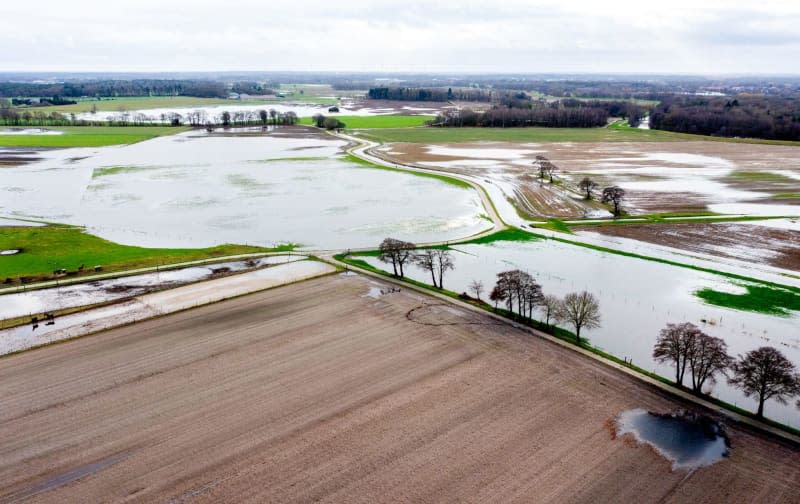 An aerial view taken with a drone shows flooded fields and meadows around the Buemmersteder Fleth in the Huntemarsch. The flood situation remains tense in many regions of Lower Saxony over the Christmas holidays. Hauke-Christian Dittrich/dpa