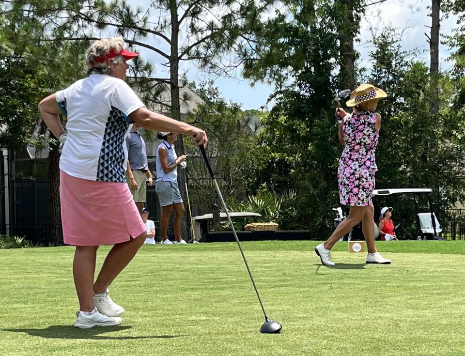 Seven-time LPGA winner Michelle McGann follows through on her tee shot at the St. Johns Golf and Country Club's 10th hole on Wednesday, while World Golf Hall of Famer Hollis Stacy, who won 18 times, watches. The two competed in the Legends of the LPGA event to benefit the Moore-Myers Children's Fund.