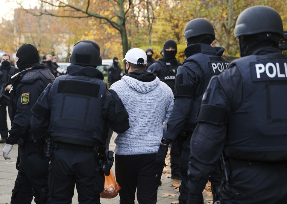 Police officers escort a person for an identity check in Berlin, Germany, Tuesday, Nov. 17, 2020. Almost a year after the art theft in Dresden's Green Vault, police arrested three suspects on Tuesday morning in Berlin. Since the early morning, a total of 18 objects have been searched. (Annette Riedl/dpa via AP)