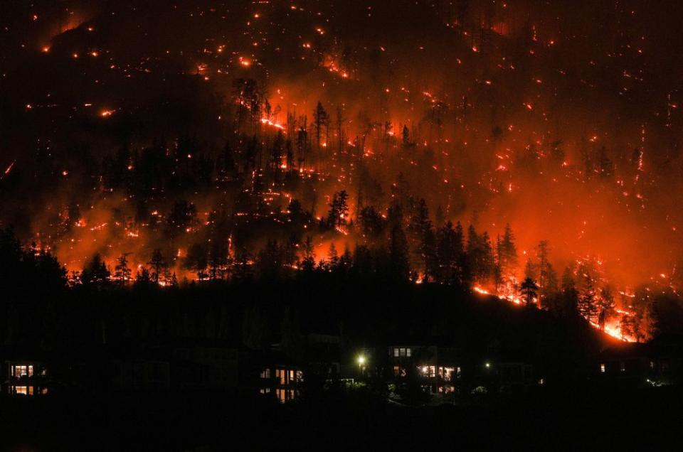 Flames from the McDougall Creek wildfire encircle a mountainside above homes in West Kelowna, British Columbia, on Aug. 18. Extreme weather conditions fueled Canada's worst wildfire season on record, with thousands of fires devastating millions of acres and darkening skies thousands of miles away.<span class="copyright">Darryl Dyck—The Canadian Press/AP</span>