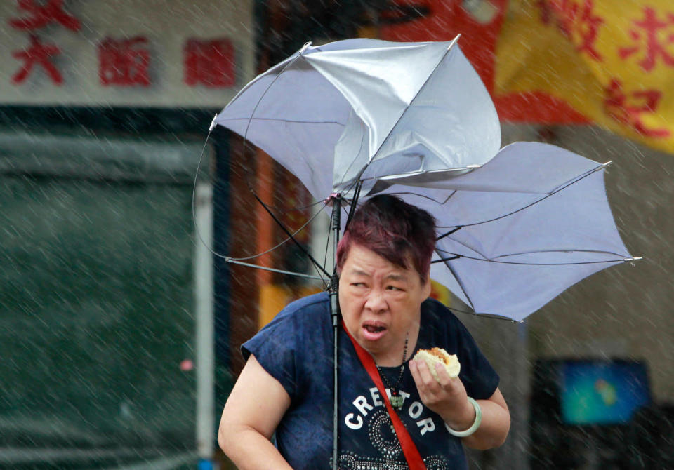 <p>A woman eats and struggles with her umbrella against powerful gusts of wind generated by typhoon Megi across the the island in Taipei, Taiwan, Tuesday, Sept. 27, 2016. Schools and offices have been closed on Taiwan and people in dangerous areas have been evacuated as a large typhoon with 162 kilometers- (100 miles-) per-hour winds approaches the island. (AP Photo/Chiang Ying-ying)</p>
