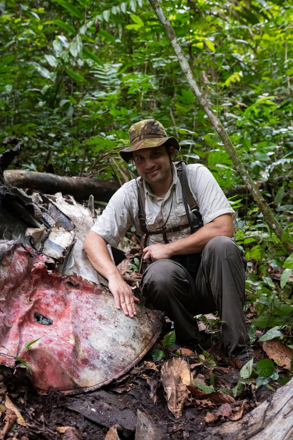 Justin Taylan, director of Pacific Wrecks, is shown here at the P-38 wreck site, leaning on the tip of the plane's wing, which was painted red.