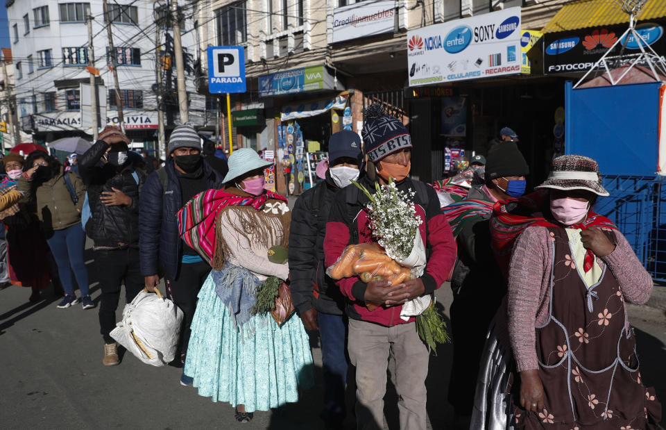 Varias personas hacen fila mientras esperan el transporte público en medio de la pandemia de coronavirus el lunes 25 de mayo de 2020, en El Alto, Bolivia. La ciudad está limitando el acceso al transporte público en función de los números de documentos de identidad de los residentes. (Foto AP/Juan Karita)
