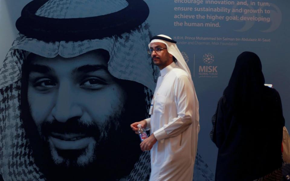 A participant walks next to a picture of Saudi Crown Prince Mohammed bin Salman during the Misk Global Forum in Riyadh - REUTERS