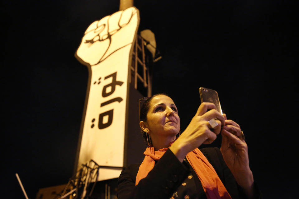 In this Friday, Nov. 8, 2019 photo Singer Tania Saleh takes pictures by her mobile phone at the martyrs square where the ongoing anti-government take place everyday, in downtown Beirut, Lebanon. Saleh grew up amid a civil war that has robbed her of her childhood. Of her friends and neighbors. And of the Lebanon she so loved. (AP Photo/Hussein Malla)