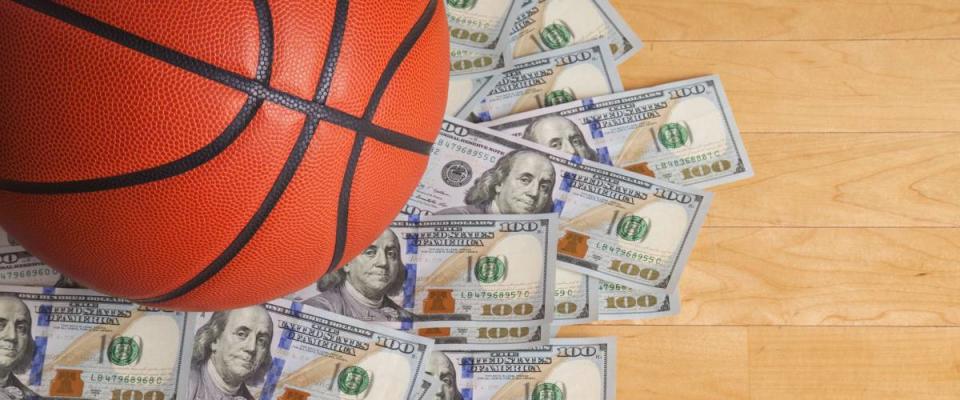 A basketball on a pile of one hundred dollar bills viewed from above