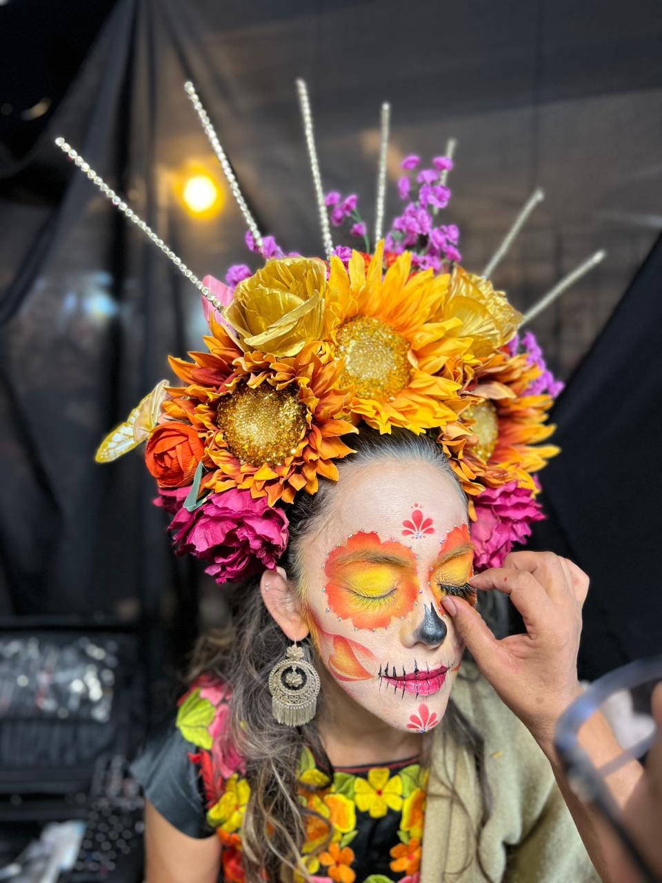A makeup artist applies a false eyelash to Fernanda Tarr of Los Angeles at the Día de Los Muertos celebration at the Hollywood Forever Cemetery in Los Angeles on Saturday, Oct. 28, 2023.