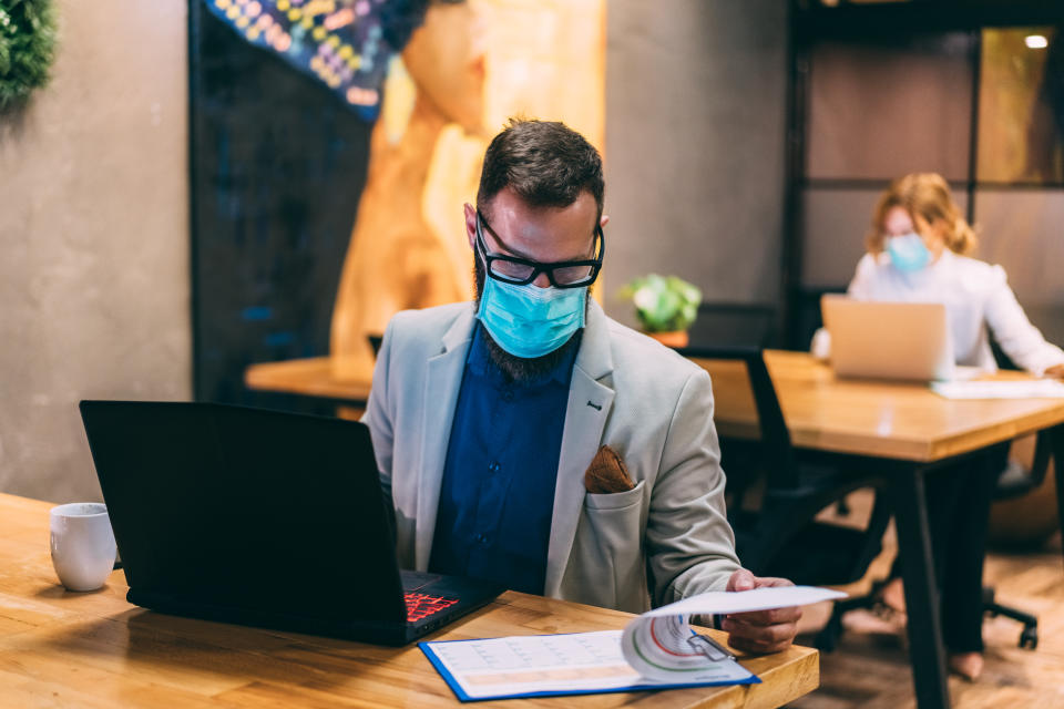 Businesspeople wearing masks in the office and working on bigger distance for safety during COVID-19 pandemic