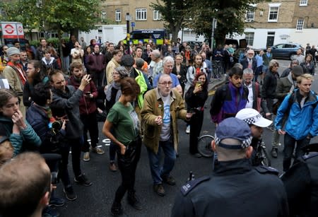People are seen outside as police officers raid an Extinction Rebellion storage facility, at Lambeth County Court, in London