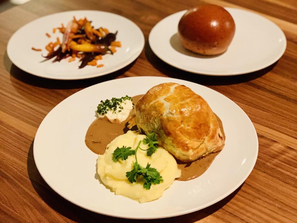 White plates with Beef Wellington, carrots, and roll from Alinea