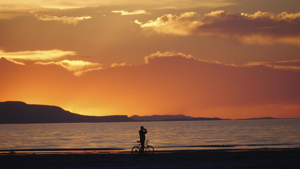 A man on a bike photographs the sunset at the Great Salt Lake Thursday June 13, 2024, near Salt Lake City. (AP Photo/Rick Bowmer)