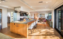 <p>Thanks to the open concept of the home, the gourmet kitchen, which features gorgeous verde quartz countertops and a center island with a breakfast bar, looks right over to the adjoining family room.</p>
