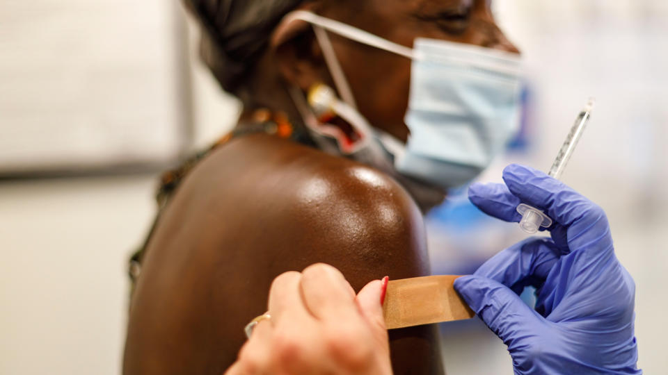 A nurse places a bandage on a woman's arm 
