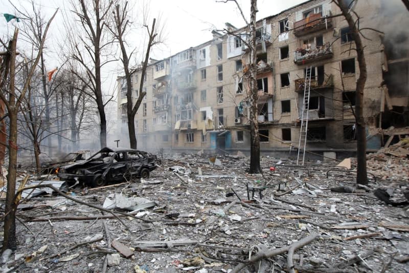 Debris covers the ground around a burnt-out car and outside a destroyed residential building after a Russian missile attack on Kharkiv. -/Ukrinform/dpa