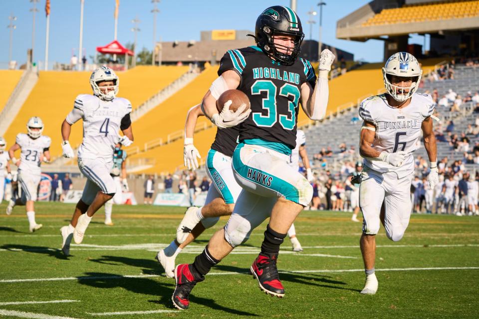 Highland Hawks running back Eli Kerby (33) runs the ball along the sidelines as Pinnacle Pioneers defensive backs Jadiem Birthwright (6) and Luc Baker (4) during the 6A state championship game at Sun Devil Stadium in Tempe on Dec. 10, 2022.