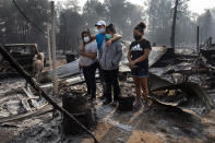 FILE - In this Sept. 10, 2020, file photo, The Reyes family looks at the destruction of their home at Coleman Creek Estates mobile home park in Phoenix, Ore. The area was destroyed when a wildfire swept through on Sept. 8. (AP Photo/Paula Bronstein, File)