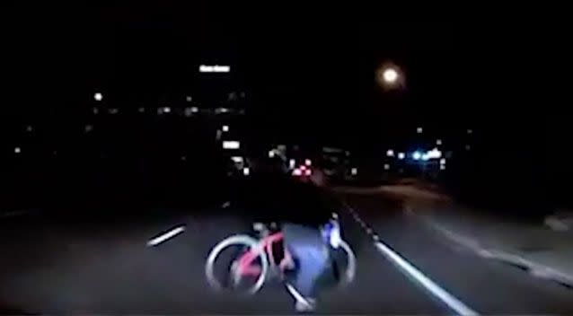 The woman appears in the headlights pushing a bicycle across the middle of the road. Source: Tempe Police