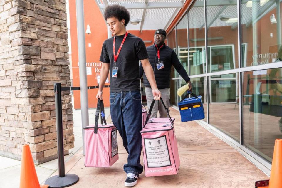 Sacramento ballot transporters James Hill Jr. and his father James Hill Sr. take filled voting containers from the Robbie Waters Pocket-Greenhaven library to the county elections office on Tuesday, March 5, 2024.