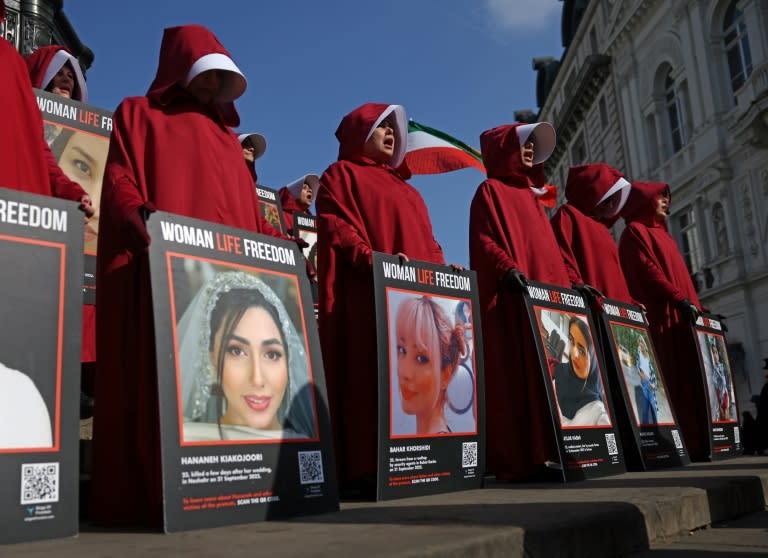 Manifestantes vestidas con una indumentaria parecida a la de la serie de televisión El cuento de la criada portan carteles en una protesta para exigir que se protejan los derechos de las muejres en Irán, en Piccadilly Circus, Londres, el 8 de marzo de 2024 (Daniel LEAL)