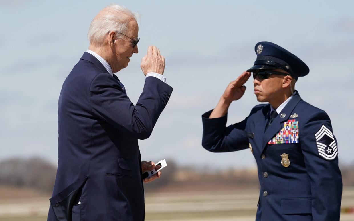 Joe Biden, the US President, holds eclipse glasses as he gets to Air Force One to depart from Madison, Wisconsin