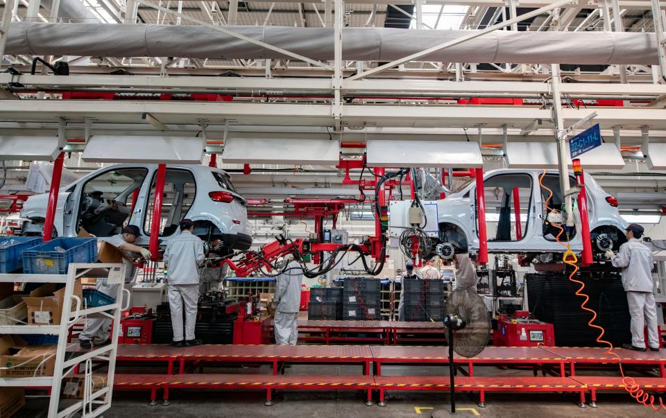 Employees work on the assembly line of new energy vehicles at a factory.