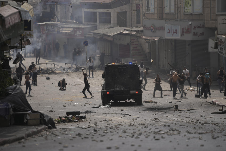 Palestinians clash with Palestinian security forces following an arrest raid against local militants, in the West Bank city of Nablus Tuesday, Sept. 20, 2022. Palestinian security forces on Tuesday exchanged fire with militants in the center of the West Bank's second-largest city, as angry residents pelted an armored jeep with objects and chased it away. One man was reported dead. The incident, sparked by an arrest raid against local militants, marked a rare case of deadly internal Palestinian fighting in the occupied West Bank. (AP Photo/Nasser Nasser)