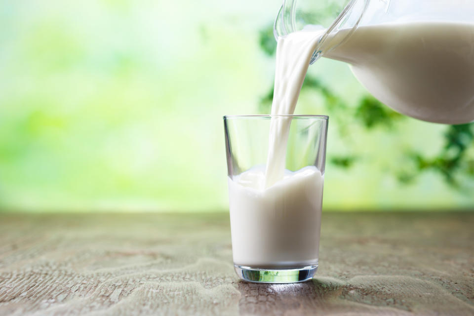 A glass pitcher pours milk into a glass