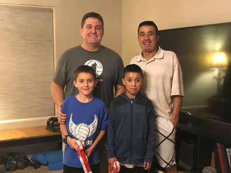 Asylum seeker host family Peter Apostol (L) and his son Teddy, 9, stand at their home with Guatemalan asylum seeker Guadalupe and his son Frasier, 12, after playing a game of laser tag in Chandler, Arizona, in this October 17, 2018 handout photo. Courtesy of Apostol Family/Handout via REUTERS