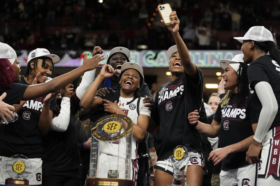 South Carolina guard MiLaysia Fulwiley, middle, celebrates with the trophy and teammates after their win against LSU in an NCAA college basketball game at the Southeastern Conference women's tournament final Sunday, March 10, 2024, in Greenville, S.C. (AP Photo/Chris Carlson)