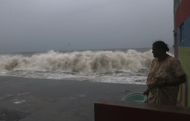 A woman watches waves splash on shores of the Arabian Sea in Mumbai, India (Rafiq Maqbool/AP)