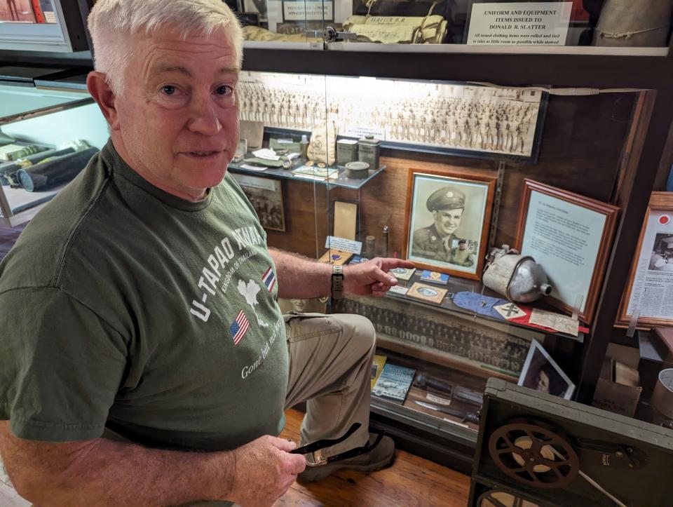 Rex Postlethwait, curator for the Northcoast Veterans Museum, points out a shot-up canteen. It floated ashore at Normandy and was brought back from Omaha Beach on the 50th anniversary of D-Day by D-Day veteran Jules Desgains of Pittsburgh.