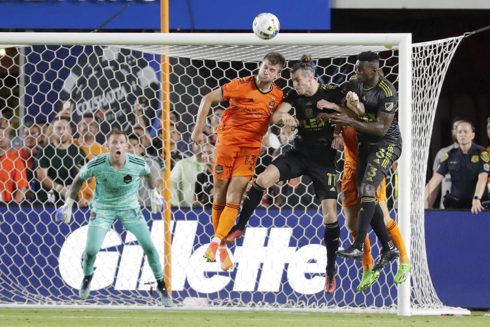 Houston Dynamo goalkeeper Steve Clark, left, looks on as defender Ethan Bartlow (13) headers away a shot on goal over Los Angeles FC midfielders Gareth Bale (11) and defender Jesus Murillo (3) during the second half of an MLS soccer match Wednesday, Aug. 31, 2022, in Houston. (AP Photo/Michael Wyke)