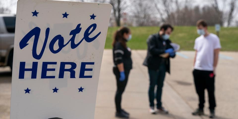 Poll worker Josh Harrison, center, works with Chad Donahue, right, during curbside voting on April 7, 2020 in Madison, Wisconsin