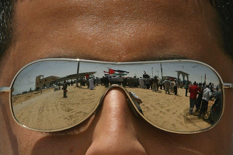 Reflected in the his glasses, a man watches a rally in support of Egypt at the Rafah border crossing with Egypt in the southern Gaza Strip. Egypt on Saturday reopened its Rafah border crossing with Gaza, allowing people to cross freely for the first time in four years, in a move hailed by Hamas but criticised by Israel