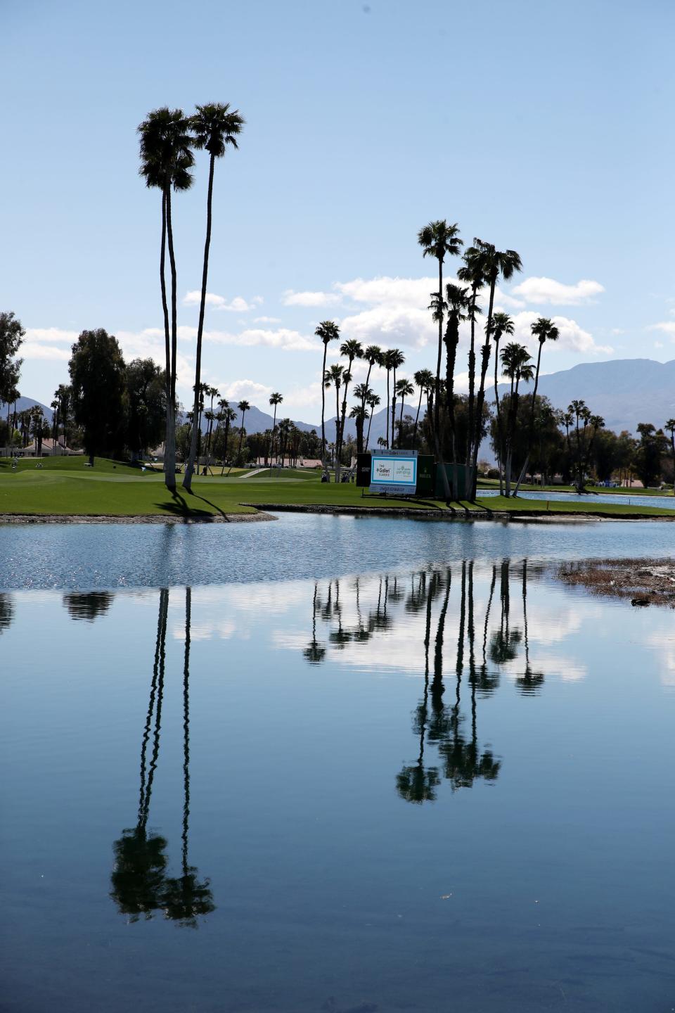 Palm trees and clouds are reflected in the pond near the 18th green at Mission Hills Country Club.