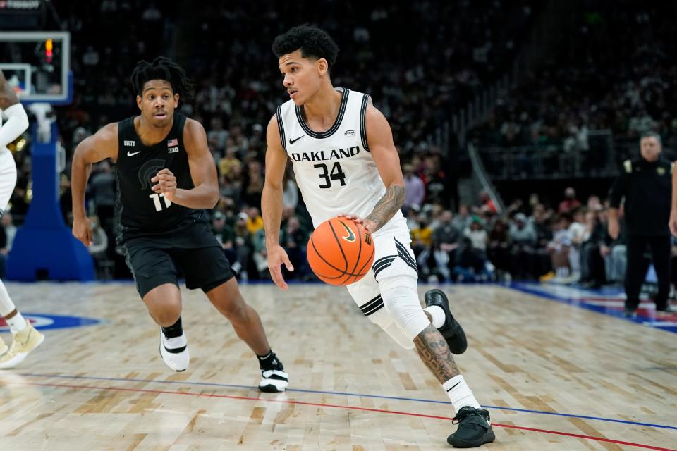 Oakland guard Jalen Moore (34) drives as Michigan State guard A.J. Hoggard (11) defends during the first half of an NCAA college basketball game, Tuesday, Dec. 21, 2021, in Detroit. (AP Photo/Carlos Osorio)