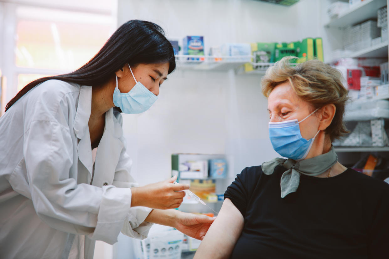 Asian nurse giving flu vaccine to a senior patient in the hospital during the global coronavirus covid-19 pandemic.