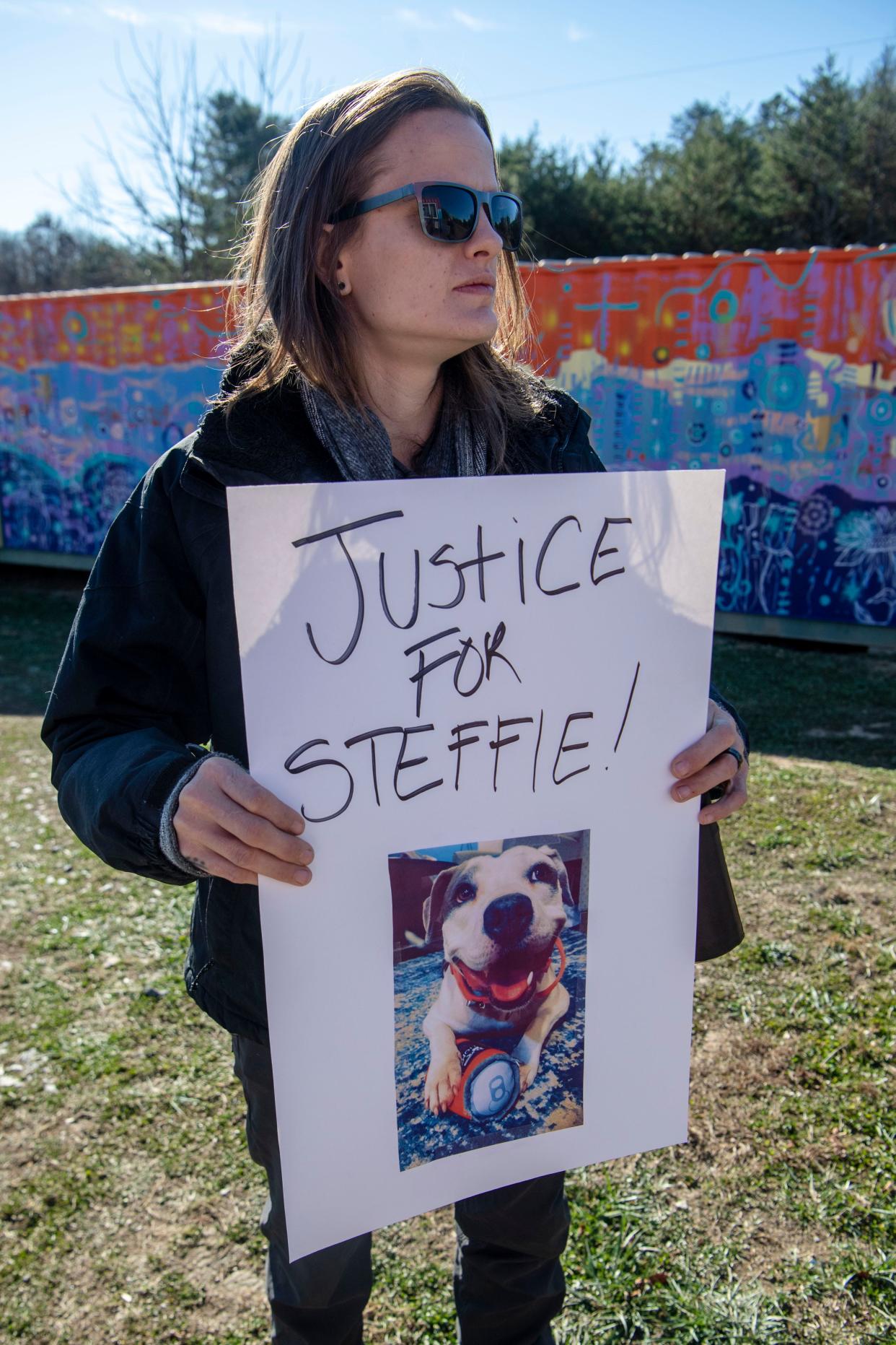 Amanda Broxterman holds a sign November 28, 2023, with a photograph of Steffie, a dog who was shot and killed by a Henderson County Sheriff’s deputy.