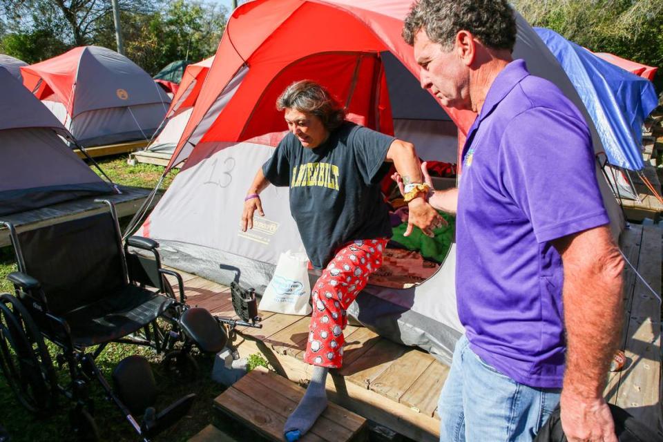 La habitante de la comunidad de tiendas Pinellas Hope Ángela Martín, en el centro, es ayudada a llegar a su silla de ruedas por el director del programa Joe Pondolfino, el martes 27 de febrero de 2024, en Clearwater.