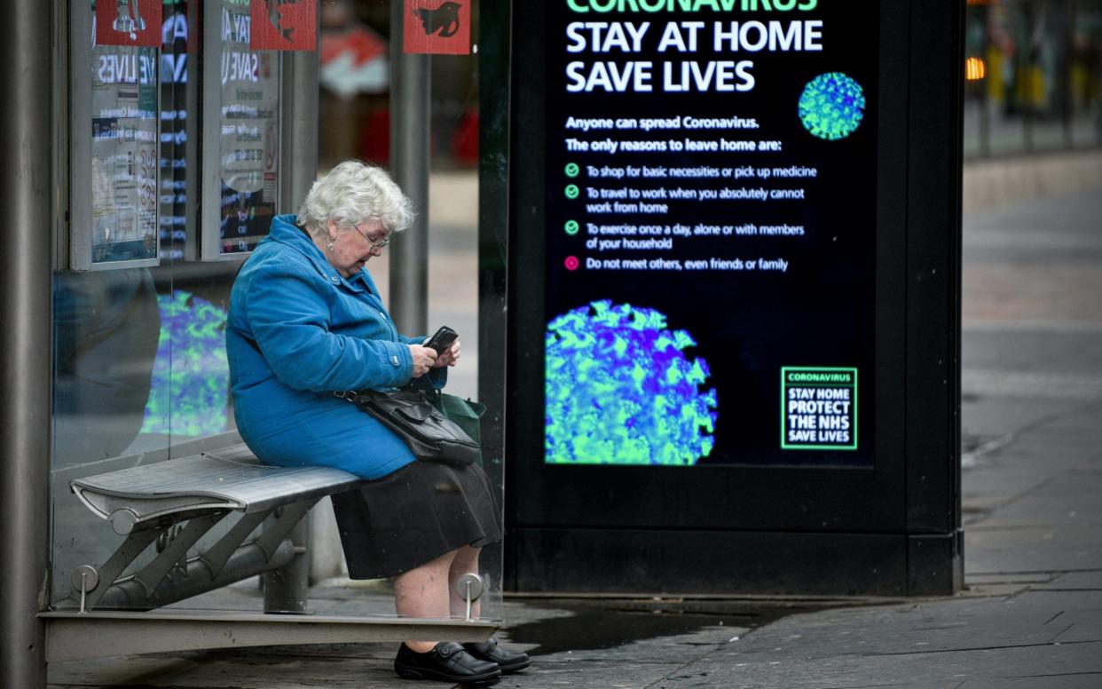 An elderly woman sits in a bus stop on Argyll Street as people are asked to socially distance themselves amid the coronavirus outbreak on March 25, 2020 in Glasgow - Jeff J Mitchell/Getty 