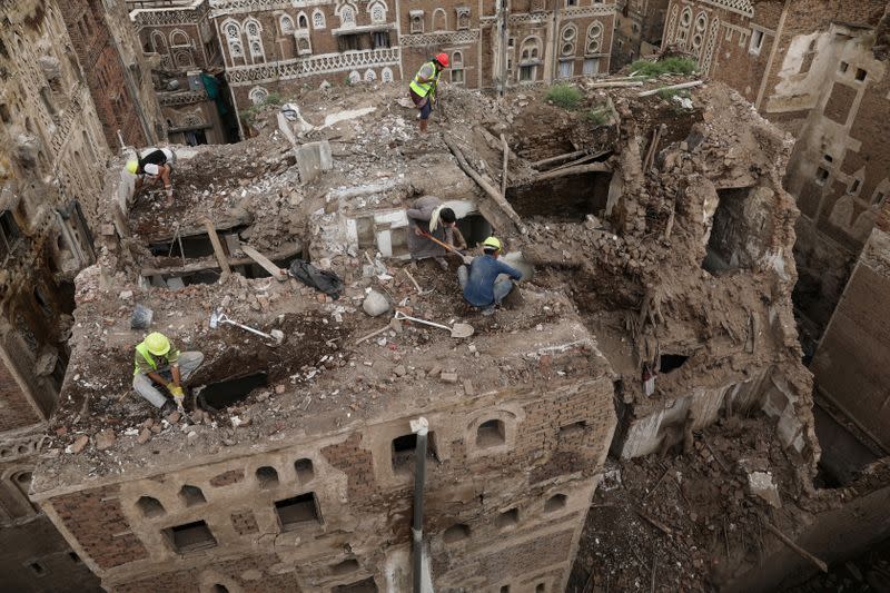 Workers demolish a building damaged by rain in the UNESCO World Heritage site of the old city of Sanaa