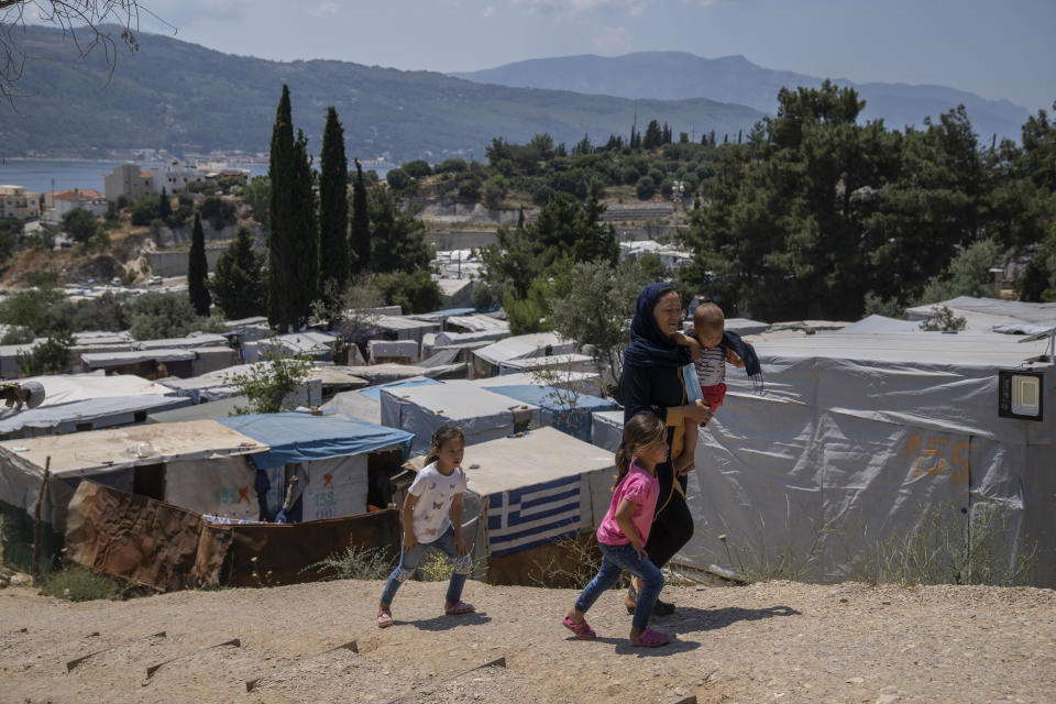 An Afghan woman with her three children walk outside the perimeter of the refugee camp at the port of Vathy on the eastern Aegean island of Samos, Greece, on Friday, June 11, 2021. An inflatable dinghy carrying nearly three dozen people reached the Greek island of Samos from the nearby Turkish coast. Within 24 hours, refugee rights groups say, the same group was seen drifting in a life raft back to Turkey. But of the 32 people determined to have initially made it to Samos, only 28 were in the raft the Turkish coast guard retrieved at sea. (AP Photo/Petros Giannakouris)