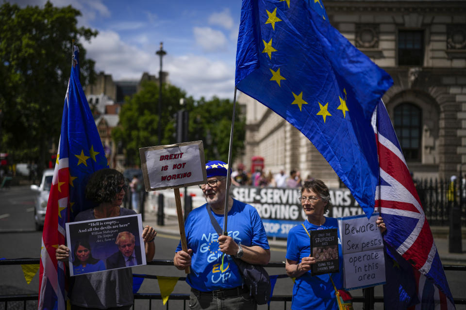 Protesters, one of them holding a photograph of British Prime Minister Boris Johnson and Britain's Home Secretary Priti Patel, stand outside the Houses of Parliament, in London, Wednesday, July 6, 2022. A defiant British Prime Minister Boris Johnson is battling to stay in power after his government was rocked by the resignation of two top ministers. His first challenge is getting through Wednesday, where he faces tough questions at the weekly Prime Minister's Questions session in Parliament, and a long-scheduled grilling by a committee of senior lawmakers. (AP Photo/Matt Dunham)