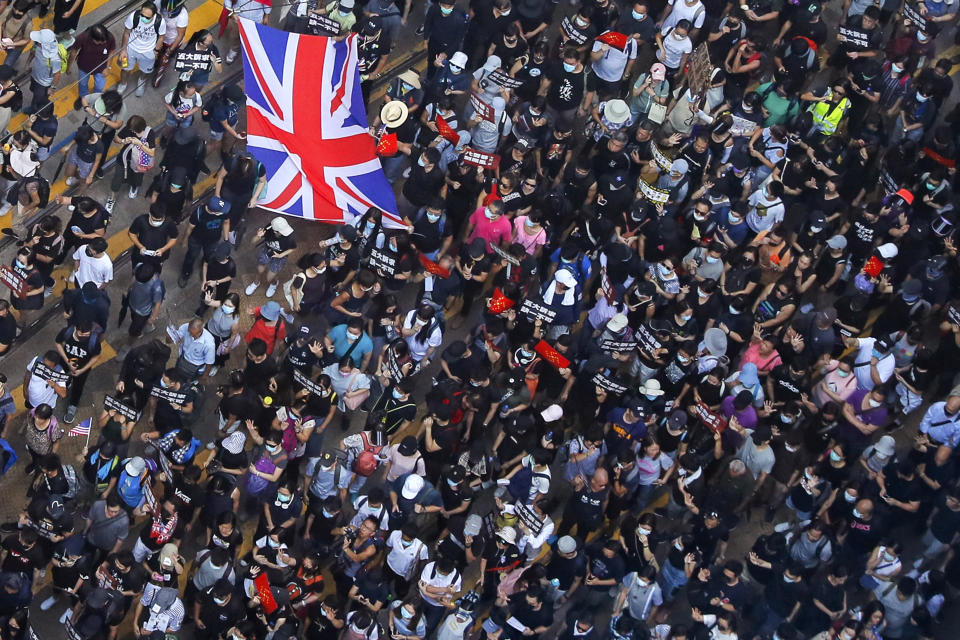 Protesters carry a British flag gather at a shopping district during a rally in Hong Kong, Sunday, Sept. 15, 2019. Thousands of Hong Kong people chanted slogans and marched Sunday at a downtown shopping district in defiance of a police ban, with shops shuttered amid fears of renewed violence in the months-long protests for democratic reforms in the semi-autonomous Chinese territory. (AP Photo/Kin Cheung)