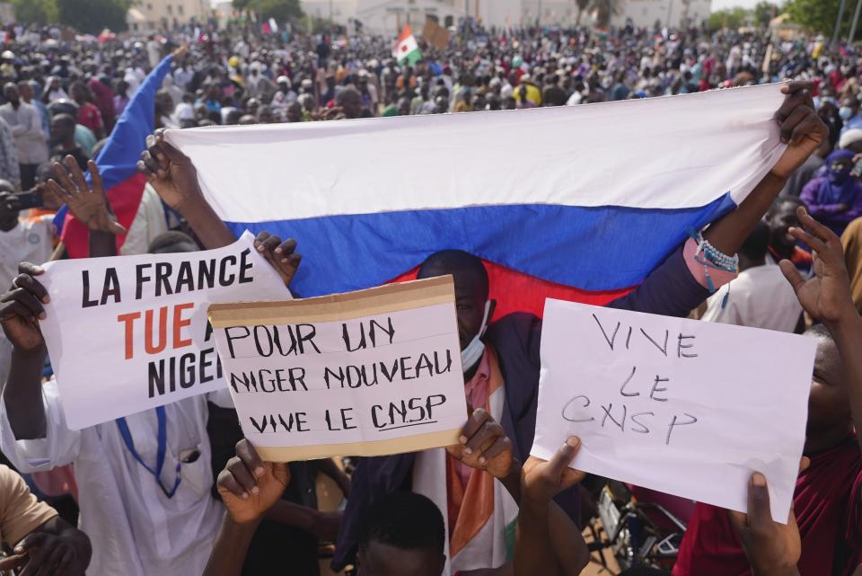 Nigeriens holding a Russian flag and placards participate in a march called by supporters of coup leader Gen. Abdourahmane Tchiani in Niamey, Niger, Sunday, July 30, 2023. Days after after mutinous soldiers ousted Niger's democratically elected president, uncertainty is mounting about the country's future and some are calling out the junta's reasons for seizing control. The signs read: "France kills Niger," and "For a new Niger long live CNSP." (AP Photo/Sam Mednick)