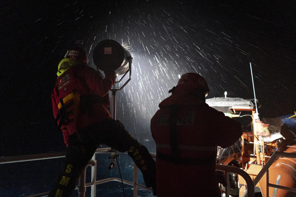 Coastguards shine a spotlight on a migrants boat before a rescue off the coast of Lampedusa on Monday Jan. 24, 2022. Seven migrants have died in a migrant crossing, the Italian Coast Guard said Tuesday after rescuing some 280 from a packed wooden boat off the Coast of Lampedusa. Most of the migrants were from Egypt and Bangladesh.(AP Photo/Pau de la Calle)