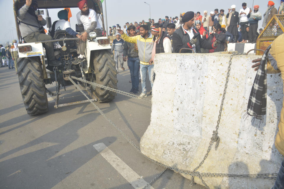 NEW DELHI, INDIA - JANUARY 26: Demonstrators removing police barricades while heading into the capital during a tractor rally on Republic Day, at Ghazipur on January 26, 2021 in New Delhi, India. Major scenes of chaos and mayhem at Delhi borders as groups of farmers allegedly broke barricades and police check posts and entered the national capital before permitted timings. Police used tear gas at Delhi's Mukarba Chowk to bring the groups under control. Clashes were also reported at ITO, Akshardham. Several rounds of talks between the government and protesting farmers have failed to resolve the impasse over the three farm laws. The kisan bodies, which have been protesting in the national capital for almost two months, demanding the repeal of three contentious farm laws have remained firm on their decision to hold a tractor rally on the occasion of Republic Day. (Photo by Sakib Ali/Hindustan Times via Getty Images)