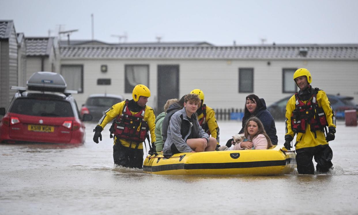 <span>Fire and rescue workers help people from holiday chalets flooded during Storm Ciaran in Burton Bradstock in November 2023.</span><span>Photograph: Finnbarr Webster/Getty Images</span>