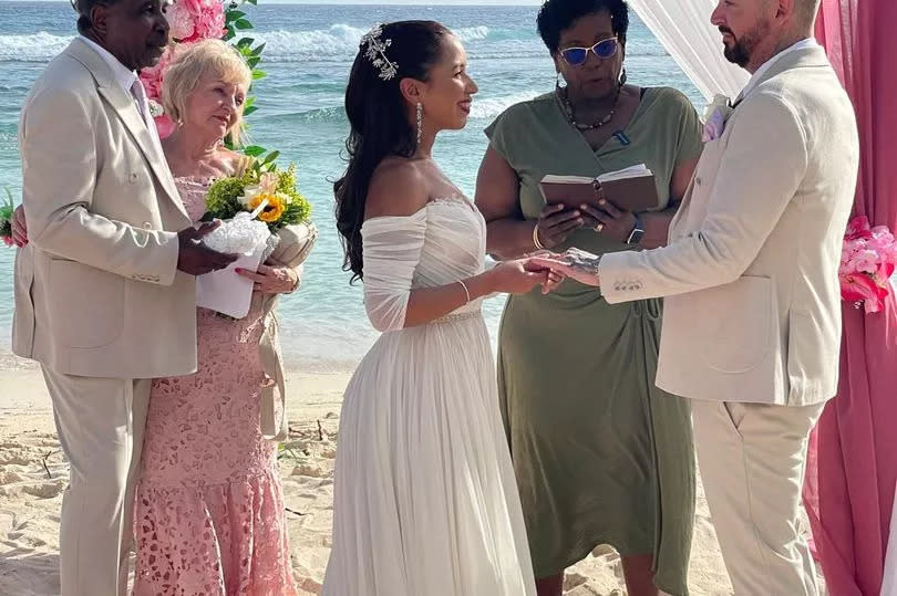 Couple getting married on a beach joined by the bride's parents