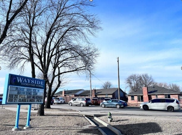 A school pickup line in front of Wayside Elementary shows how badly expansion at the school is needed. The three homes in the background were purchased by the school district. They will become a new parking lot so the school building can expand into the existing lot.